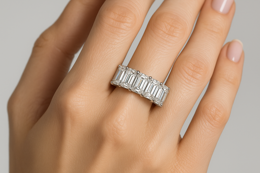 a emerald shaped diamond in a row eternity ringon a female model's hand