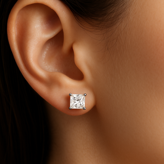 featuring a small princess cut lab grown diamond earstuds on a female model's ear, with 4 prongs setting, made with 14k white gold 